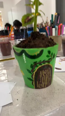 Green hand-painted pot with a monogram, planted after the workshop