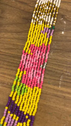 Pixel-art bead tapestry strip in pink, yellow and purple