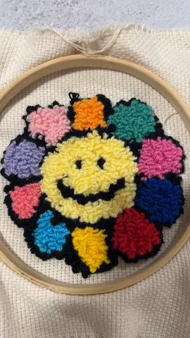 Smiley rainbow flower punch needle in an embroidery hoop