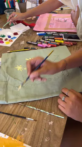 Painting yellow flowers on a sage green tote bag