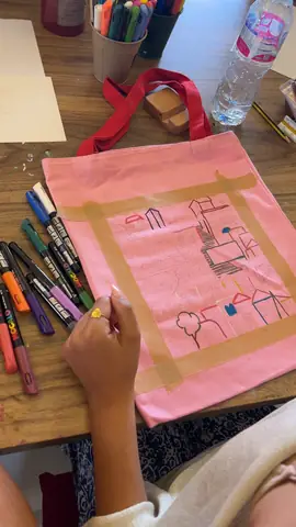 Sketching a design on a pink tote bag before painting